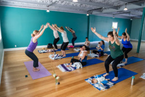 New moms practice postpartum yoga with their babies at Bring Your Own Baby yoga in the heart of Kansas City.