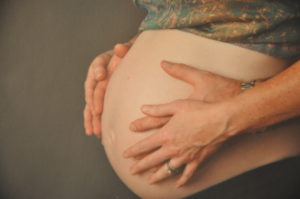 A pregnant woman holds her belly during a private yoga session in Kansas City.