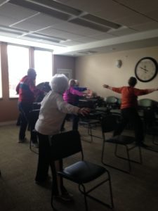 Seniors in a retirement community practice chair yoga in a class led by Jenny Hellman of Full Circle Yoga KC