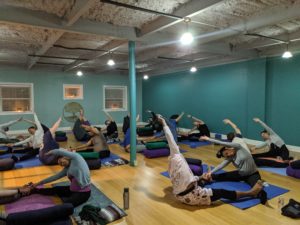 Expecting parents participate in a Partner Prenatal Yoga class at Full Circle Yoga, a prenatal yoga studio in Midtown Kansas City.
