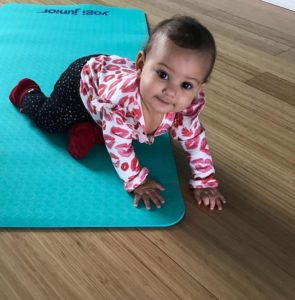A crawling baby enjoys a Parent and Little Movers toddler yoga class at Full Circle Yoga in the heart of Kansas City