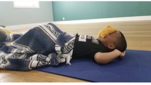 A child rests with an eye mask during toddler yoga at Full Circle Yoga in Midtown KC.