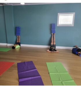 Elementary students practice legs up the wall with blocks at a social-emotional yoga class at Full Circle Yoga in Kansas City.