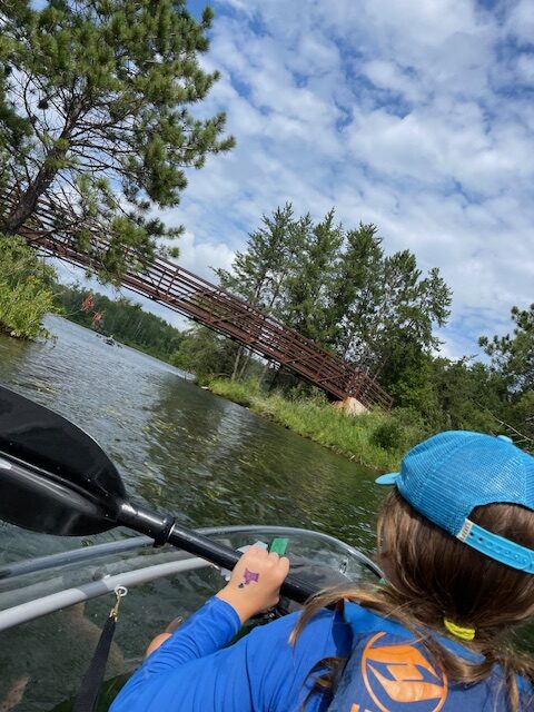 child canoeing on a lake rowing towards a bridge